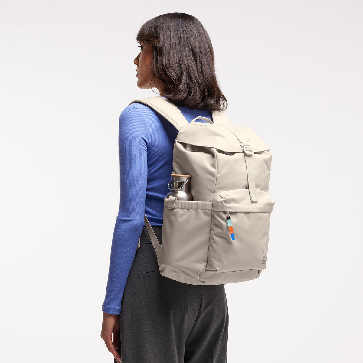 FLAP PACK Rucksack in soft shell (warmes Cremeweiß) von einer Frau auf dem Rücken getragen.