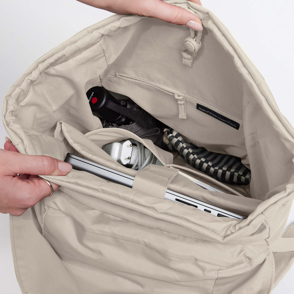 FLAP PACK Rucksack in soft shell (warmes Cremeweiß) mit Blick ins Innere, von Händen geöffnet.