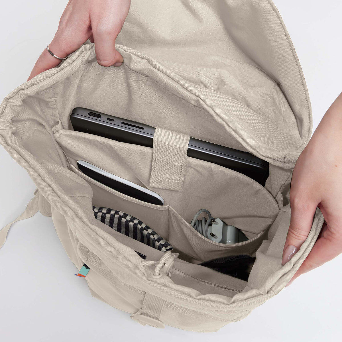 FLAP PACK Rucksack in soft shell (warmes Cremeweiß), von Händen geöffnet, zeigt die organisierte Innenansicht.
