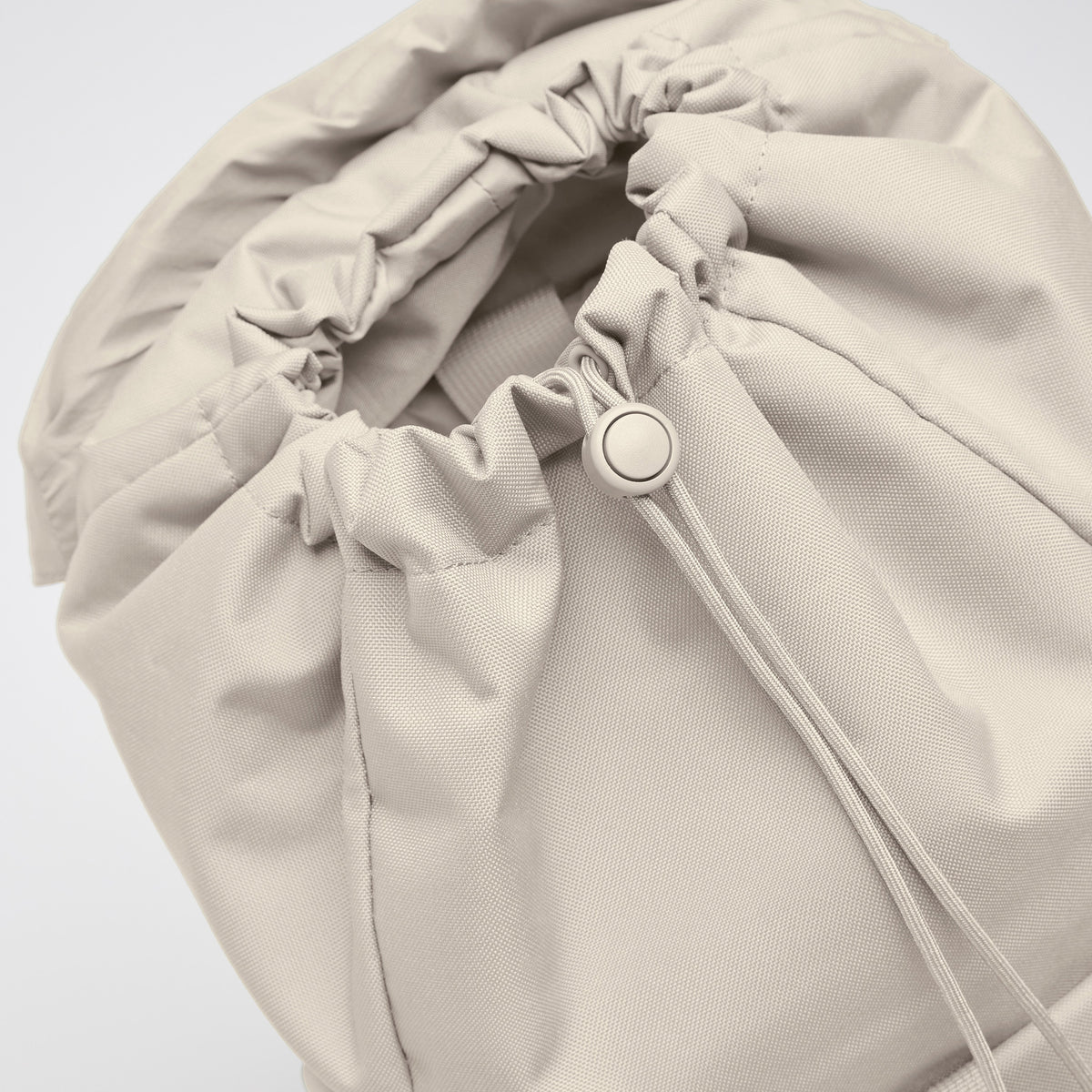 FLAP PACK Rucksack in soft shell (warmes Cremeweiß) mit geschlossenem Kordelzug und Stopper, schräge Detailansicht.