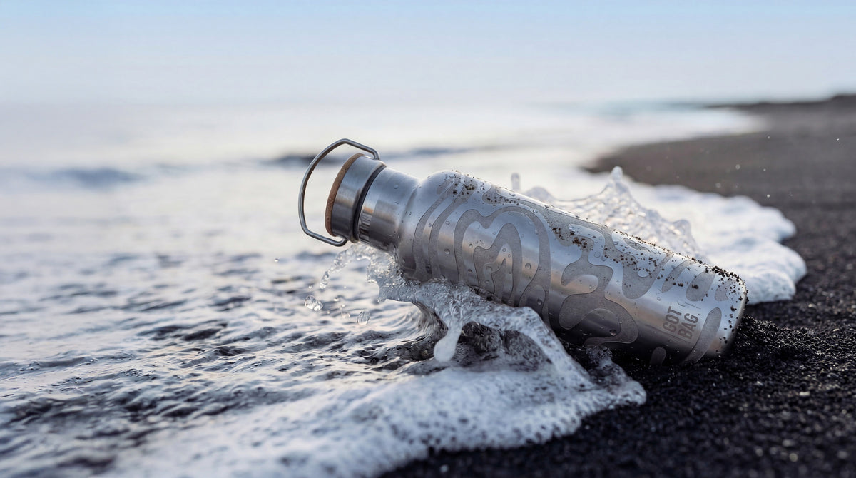 FREE BOTTLE accessorio sulla spiaggia di sabbia nera, bagnato dalle onde, con motivo e manico.