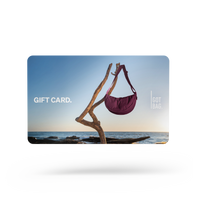 GIFT CARDS accessorio con una borsa appesa a un tronco galleggiante vicino a un mare soleggiato.
