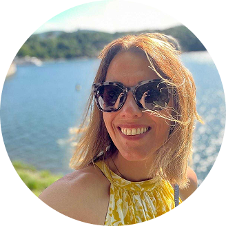 Accessories worn by a smiling woman with sunglasses outdoors by the water.