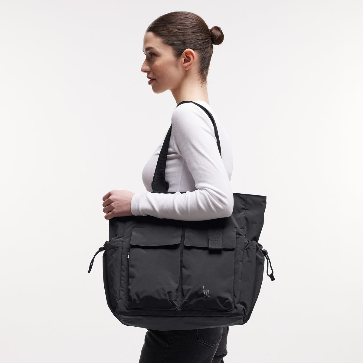 MELLOW TOTE BAG Tasche in black (Schwarz) von einer Frau über der Schulter getragen.