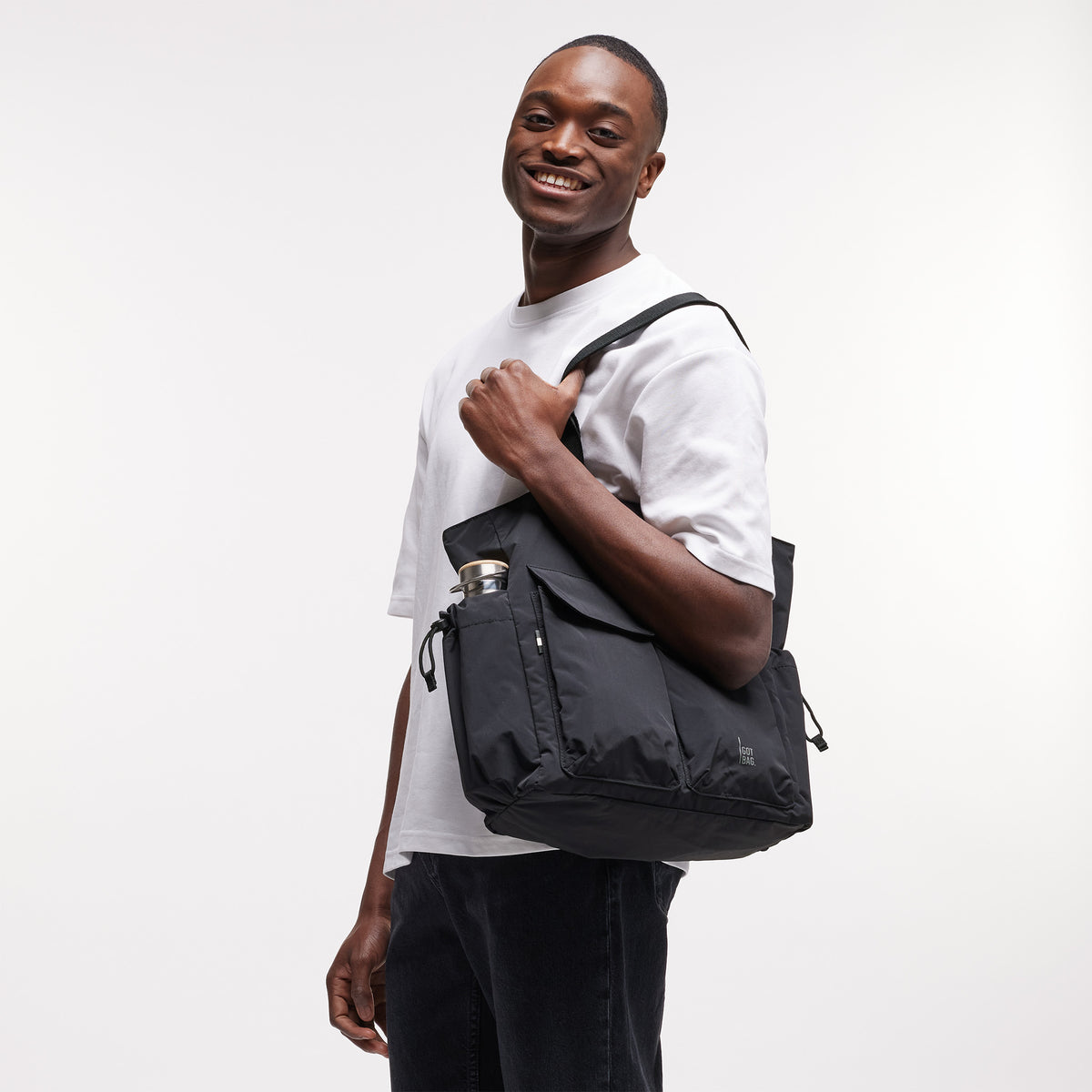 MELLOW TOTE BAG Tasche in black (Schwarz) von einem Mann über der Schulter getragen.