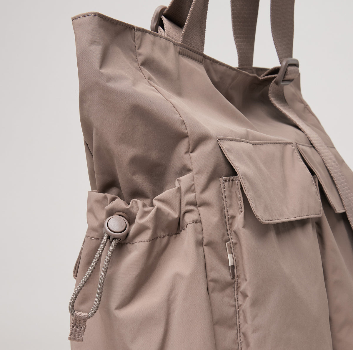 MELLOW TOTE BAG Tasche in oyster (klassisches Taupe-Braun), Detailaufnahme der Seitentasche mit Kordelzug.