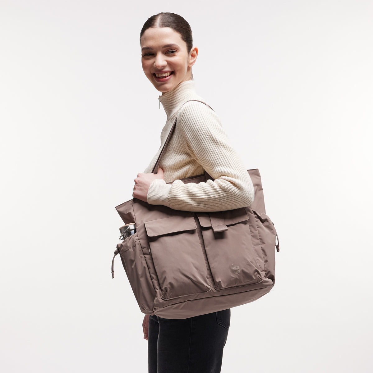 MELLOW TOTE BAG Tasche in oyster (klassisches Taupe-Braun) von einer Frau über der Schulter getragen.