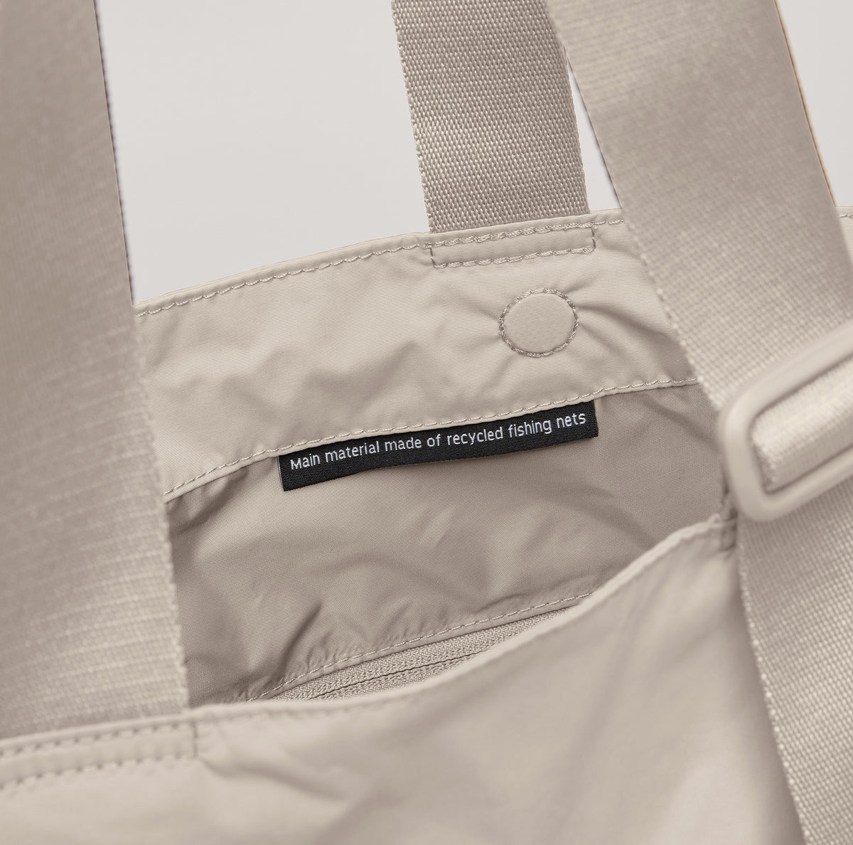MELLOW TOTE BAG Tasche in soft shell (warmes Cremeweiß), Detailaufnahme des Labels Main material made of recycled fishing nets.