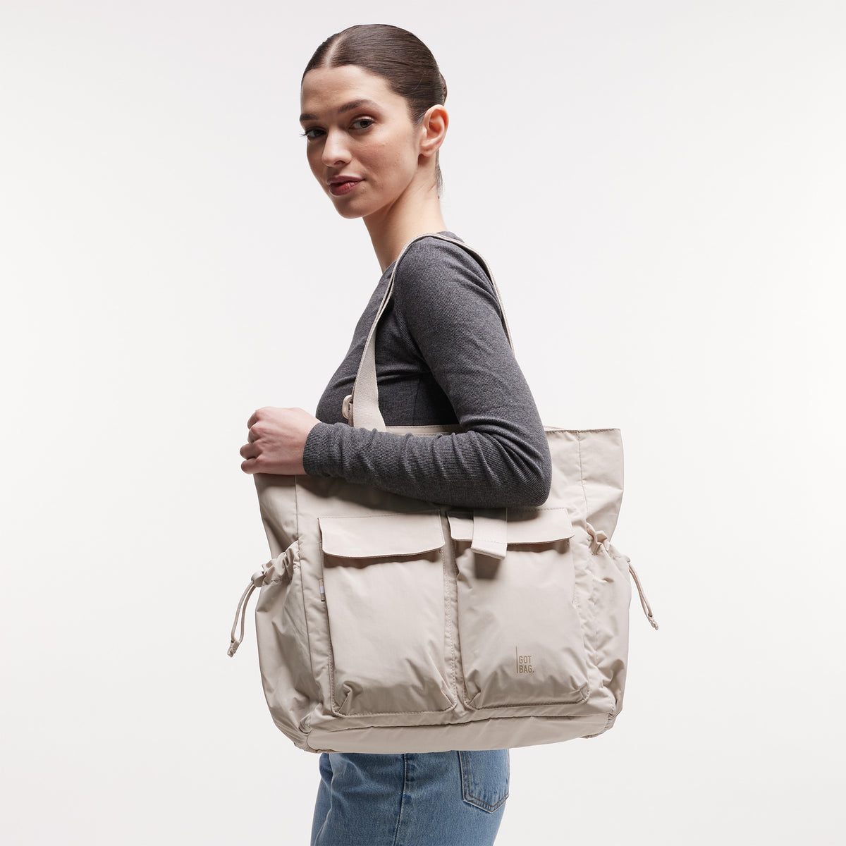 MELLOW TOTE BAG Tasche in soft shell (warmes Cremeweiß) von einer Frau über der Schulter getragen.