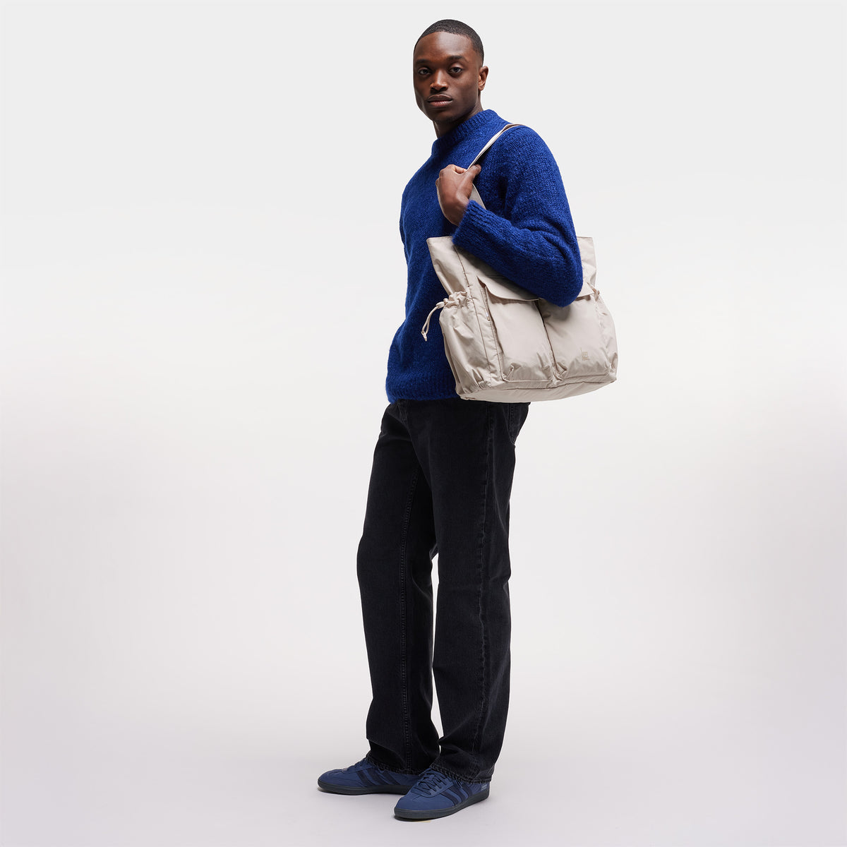MELLOW TOTE BAG Tasche in soft shell (warmes Cremeweiß) von einem Mann über der Schulter getragen.