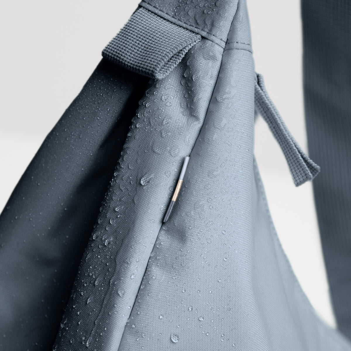 MOON BAG LARGE Tasche in marlin (grau-blau) als Detailaufnahme mit Wassertropfen auf dem Stoff.