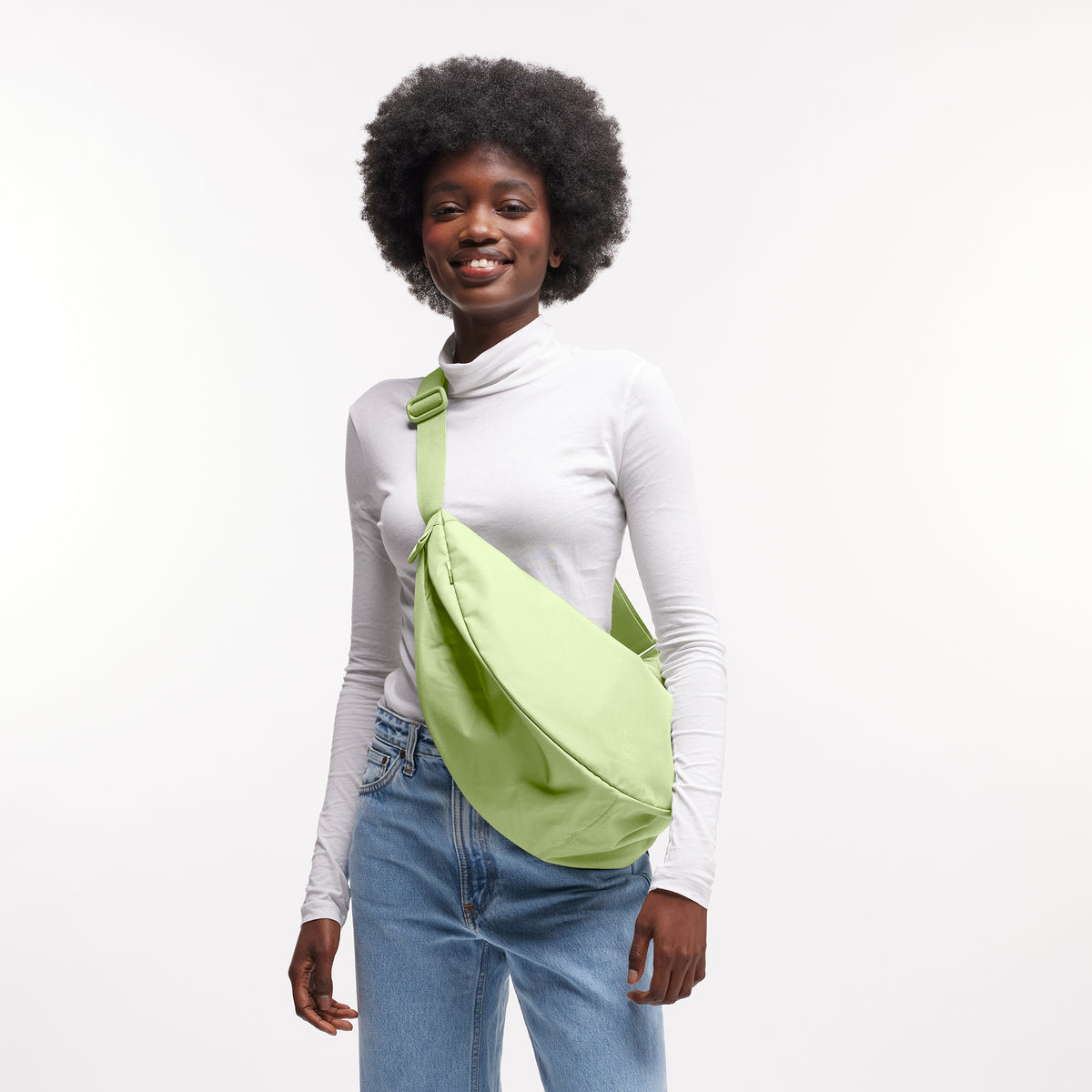 MOON BAG LARGE Tasche in wrasse (neonfarbenes Hellgrün) von einer Frau crossbody getragen.