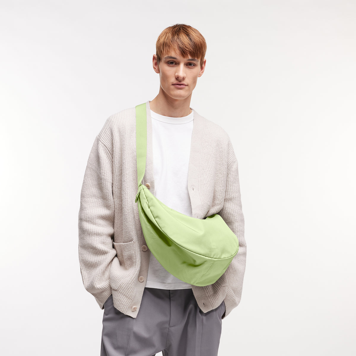 MOON BAG LARGE Tasche in wrasse (neonfarbenes Hellgrün) von einem Mann crossbody getragen.