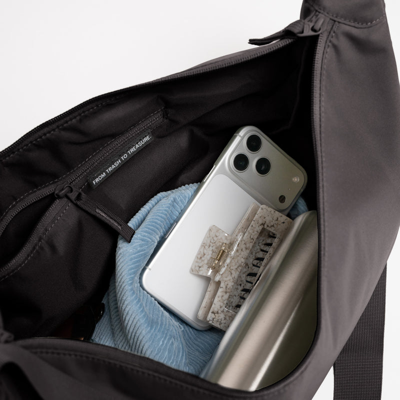 MOON BAG LARGE Tasche in mussel (dunkles Braun-Grau), Detailaufnahme des Innenraums mit Handy und Wasserflasche.