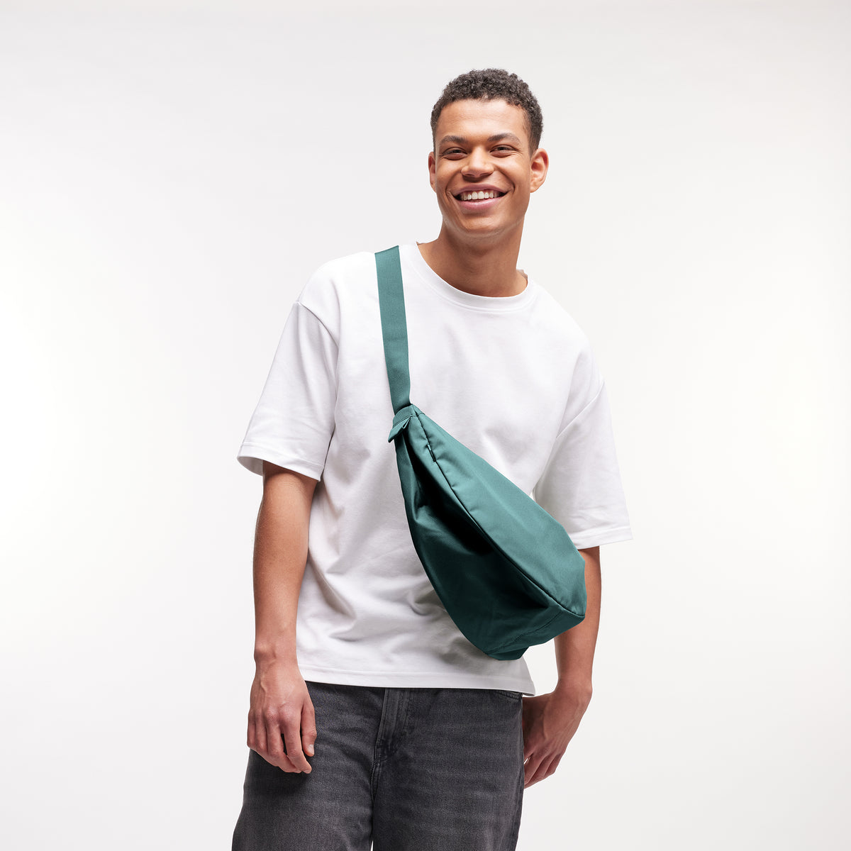 MOON BAG LARGE Tasche in sea teal (kühles Türkisgrün) von einem Mann crossbody getragen.