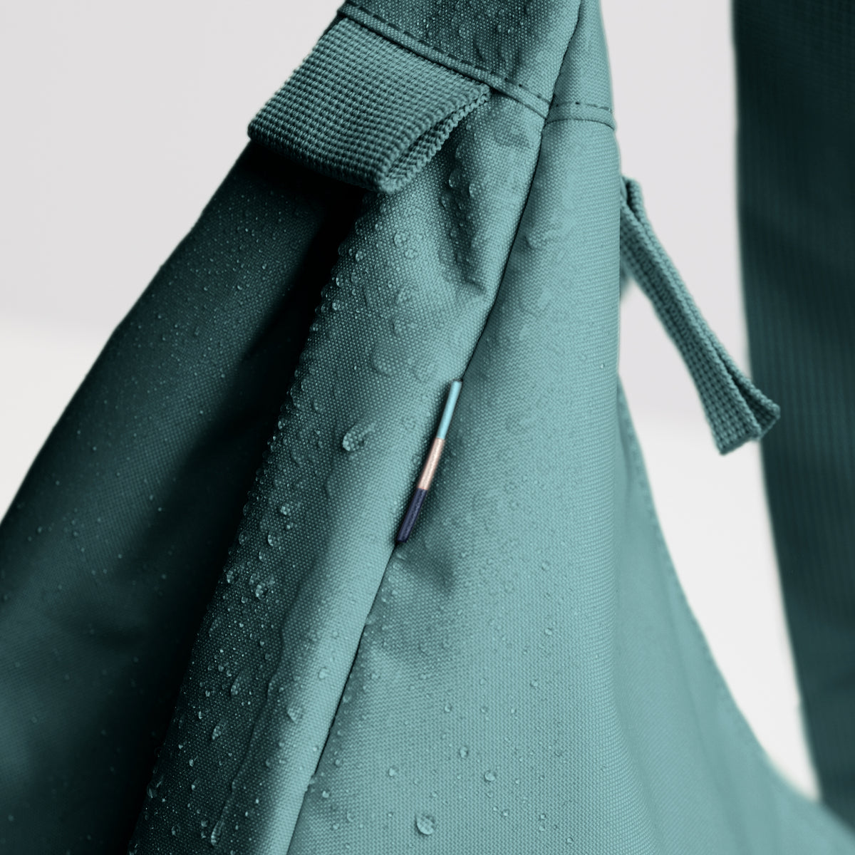 MOON BAG LARGE Tasche in sea teal (kühles Türkisgrün), Detailaufnahme mit Wassertropfen.