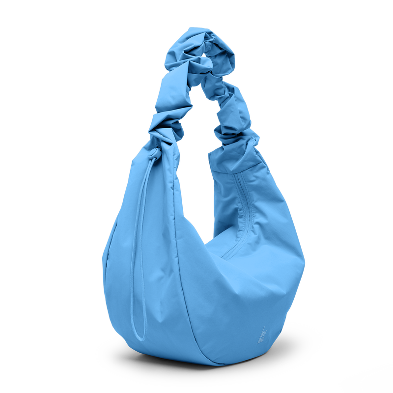 MOON BAG RUFFLE Tasche in aqua (leuchtendes Hellblau) als Studioaufnahme in diagonaler Ansicht.