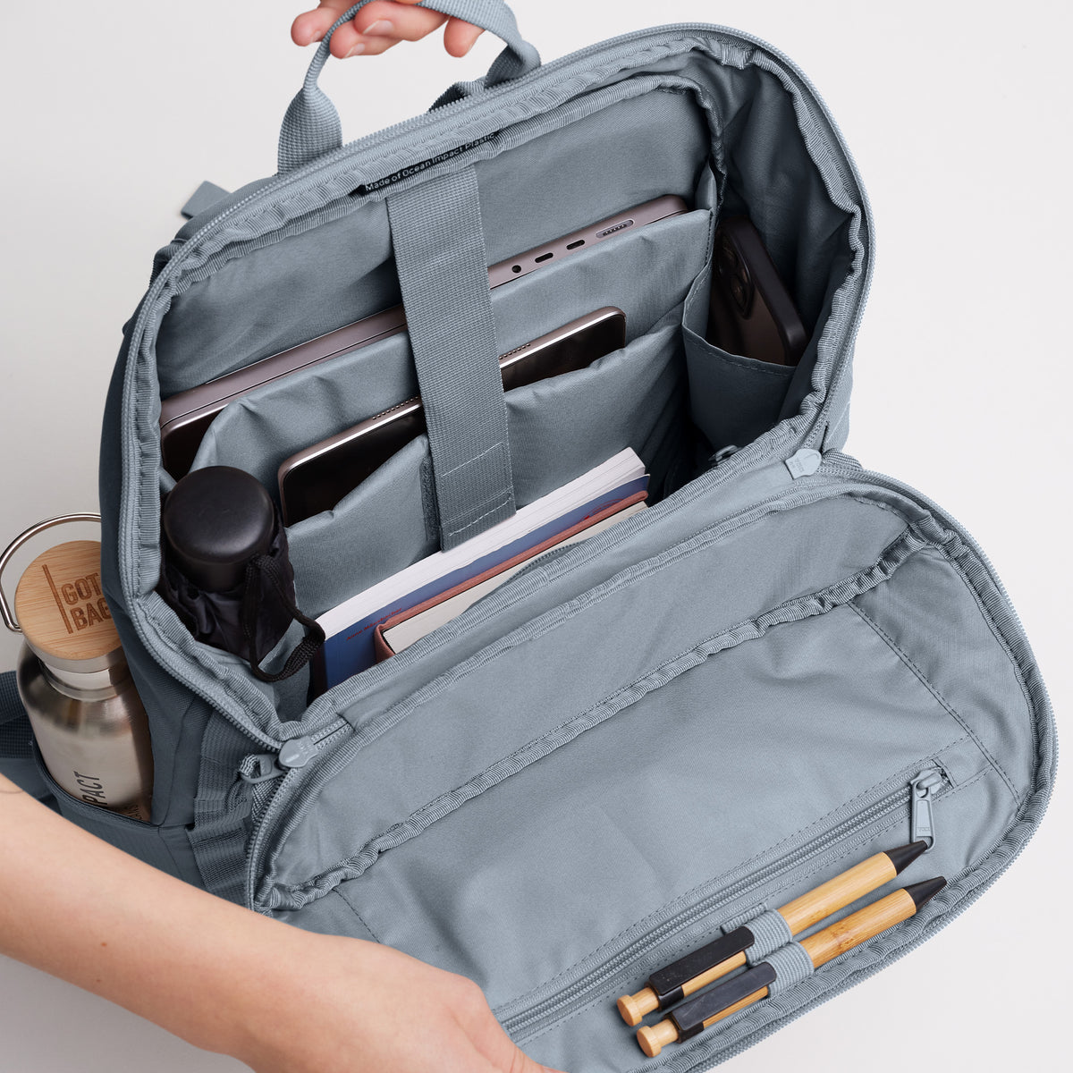 PRO PACK Rucksack in marlin (grau-blau) von Händen geöffnet, mit Blick auf die organisierte Innenausstattung.