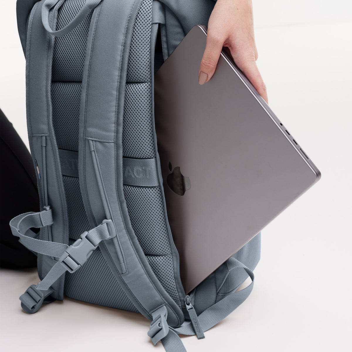 PRO PACK Rucksack in marlin (grau-blau) mit Hand, die Laptop in das Rückenabteil steckt.