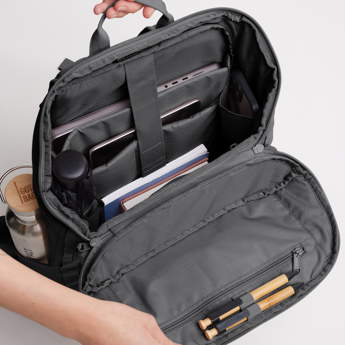 PRO PACK Rucksack in shark (Dunkelgrau), von Händen geöffnet mit Blick auf das organisierte Innere.