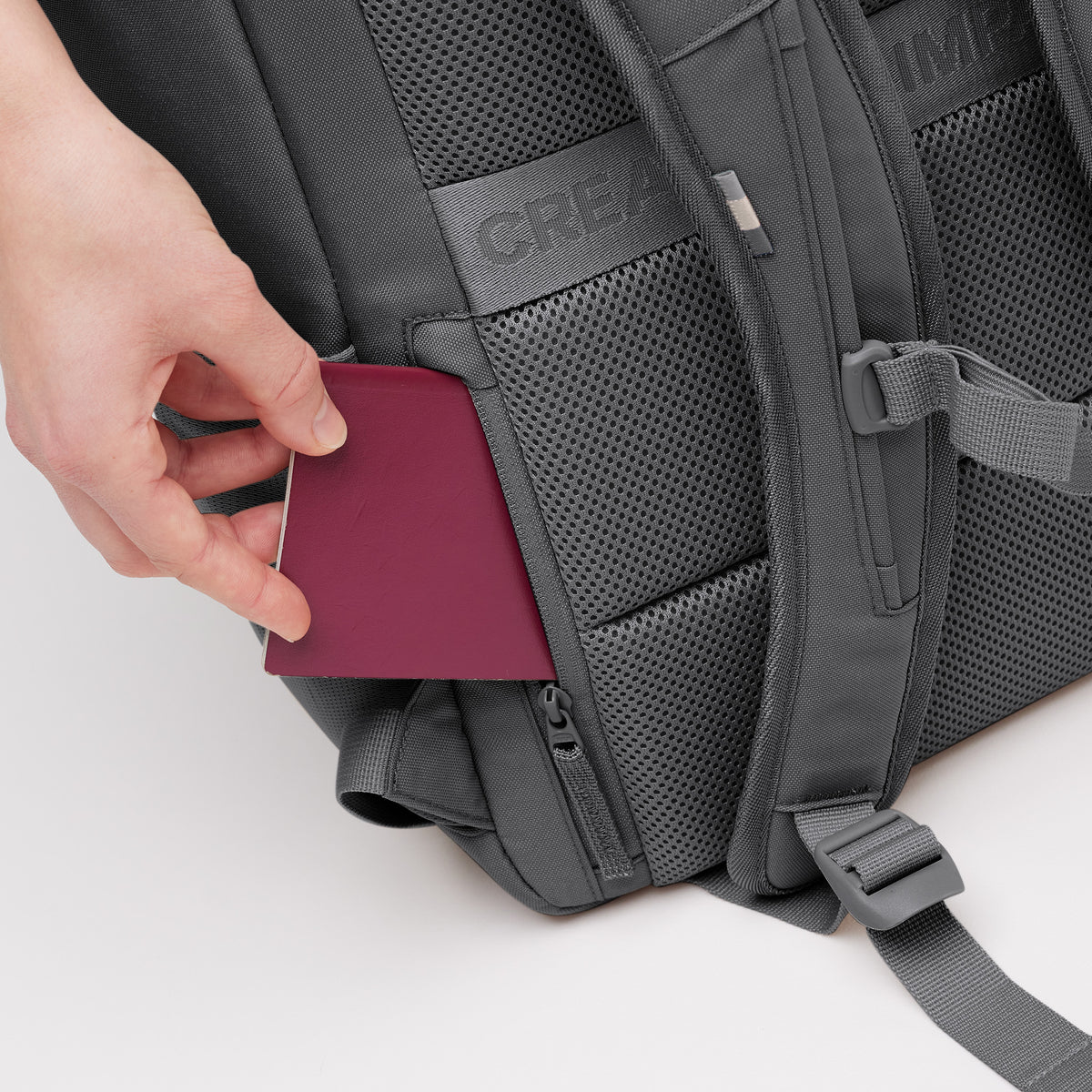PRO PACK Rucksack in shark (Dunkelgrau), eine Hand steckt einen Reisepass in die verborgene Tasche.