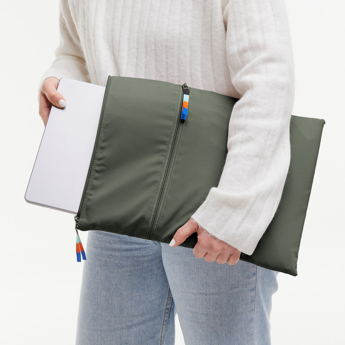 ROLLTOP Tasche in algae (Dunkelgrün mit Graustich) von einer Frau in den Händen gehalten, die einen Laptop hineinsteckt.