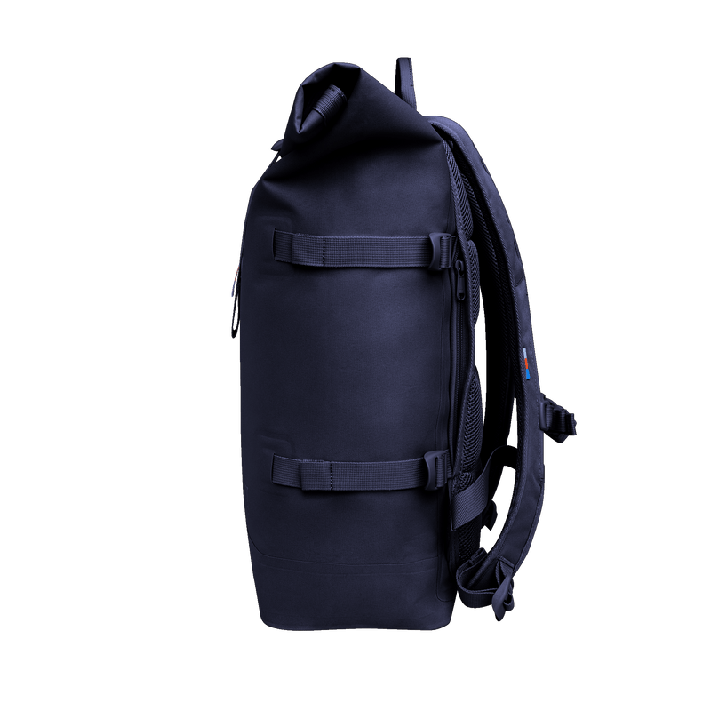 ROLLTOP Rucksack in tide (tiefes Dunkelblau mit Lilastich) als Seitenansicht.