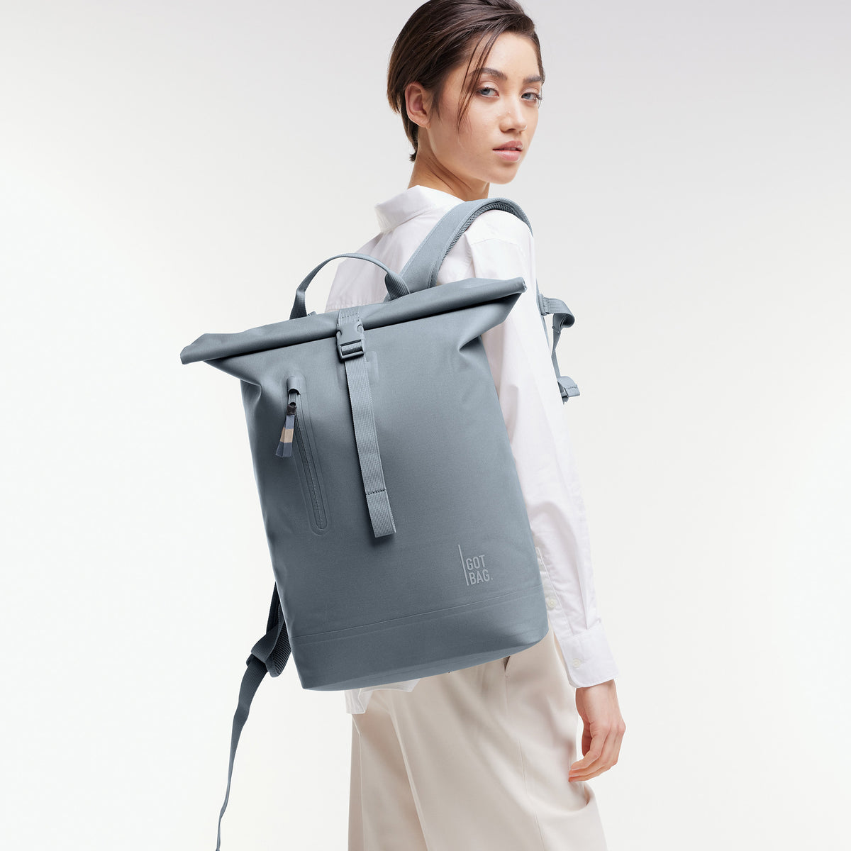 ROLLTOP LITE Rucksack in marlin (grau-blau) von einer Frau auf dem Rücken getragen.