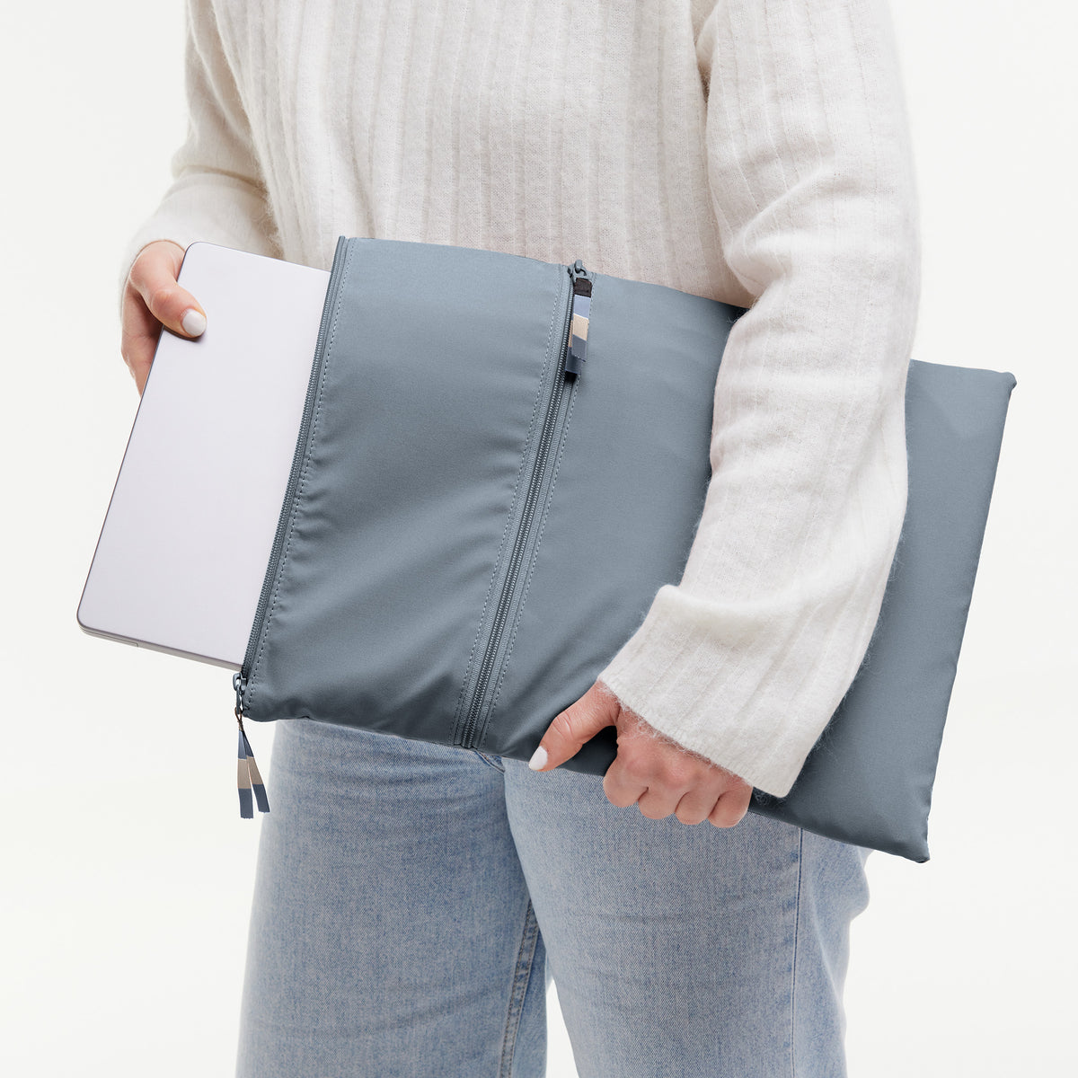 ROLLTOP LITE Tasche in marlin (grau-blau) von einer Frau mit Laptop gehalten.