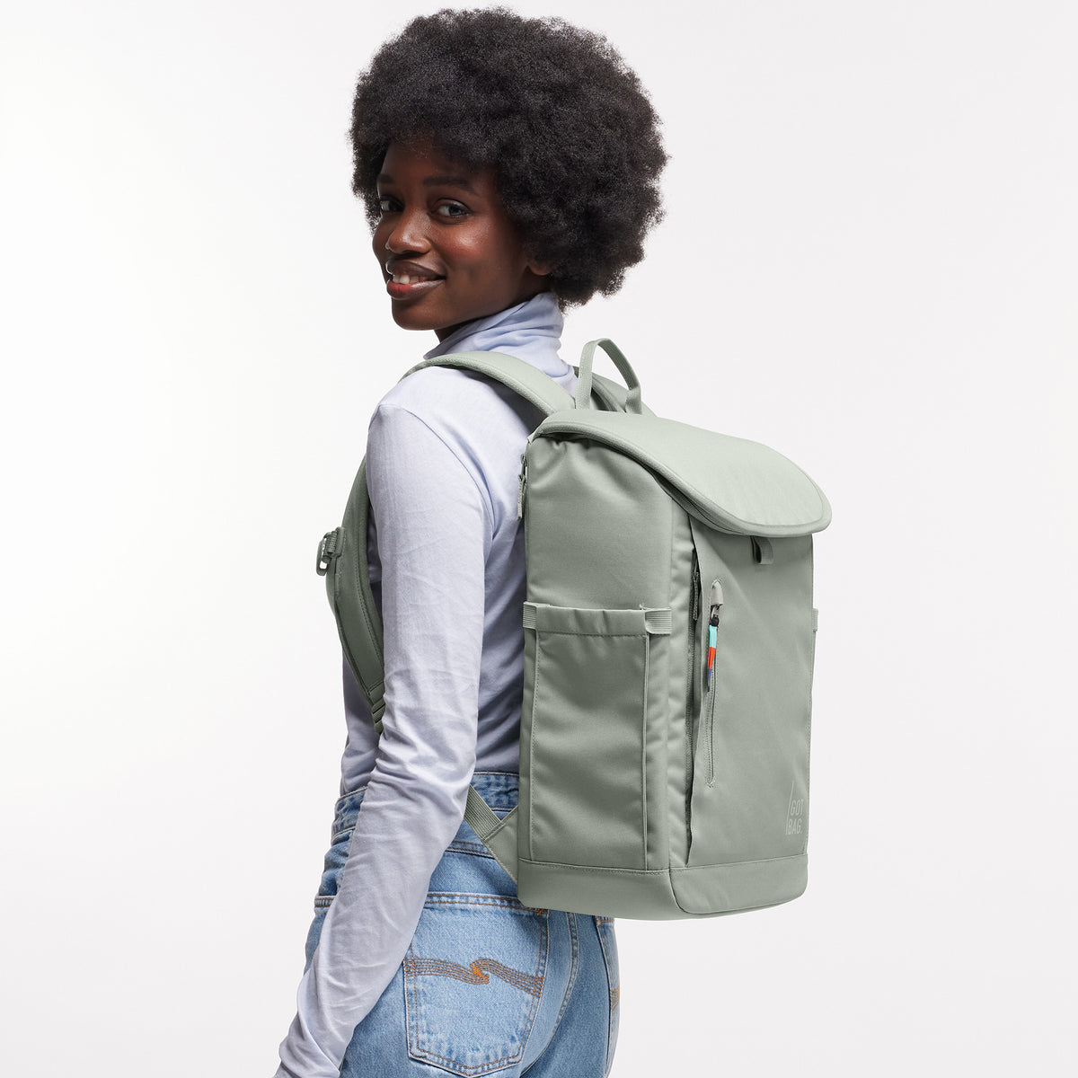 SERENE PACK Rucksack in bass (Salbeigrün) von einer Frau als Rucksack auf dem Rücken getragen.