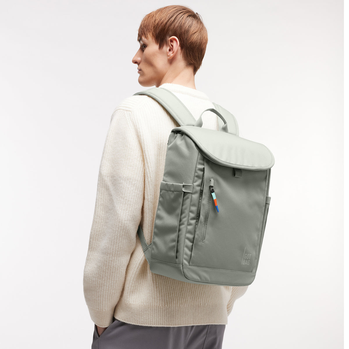 SERENE PACK Rucksack in bass (Salbeigrün) von einem Mann auf dem Rücken getragen.