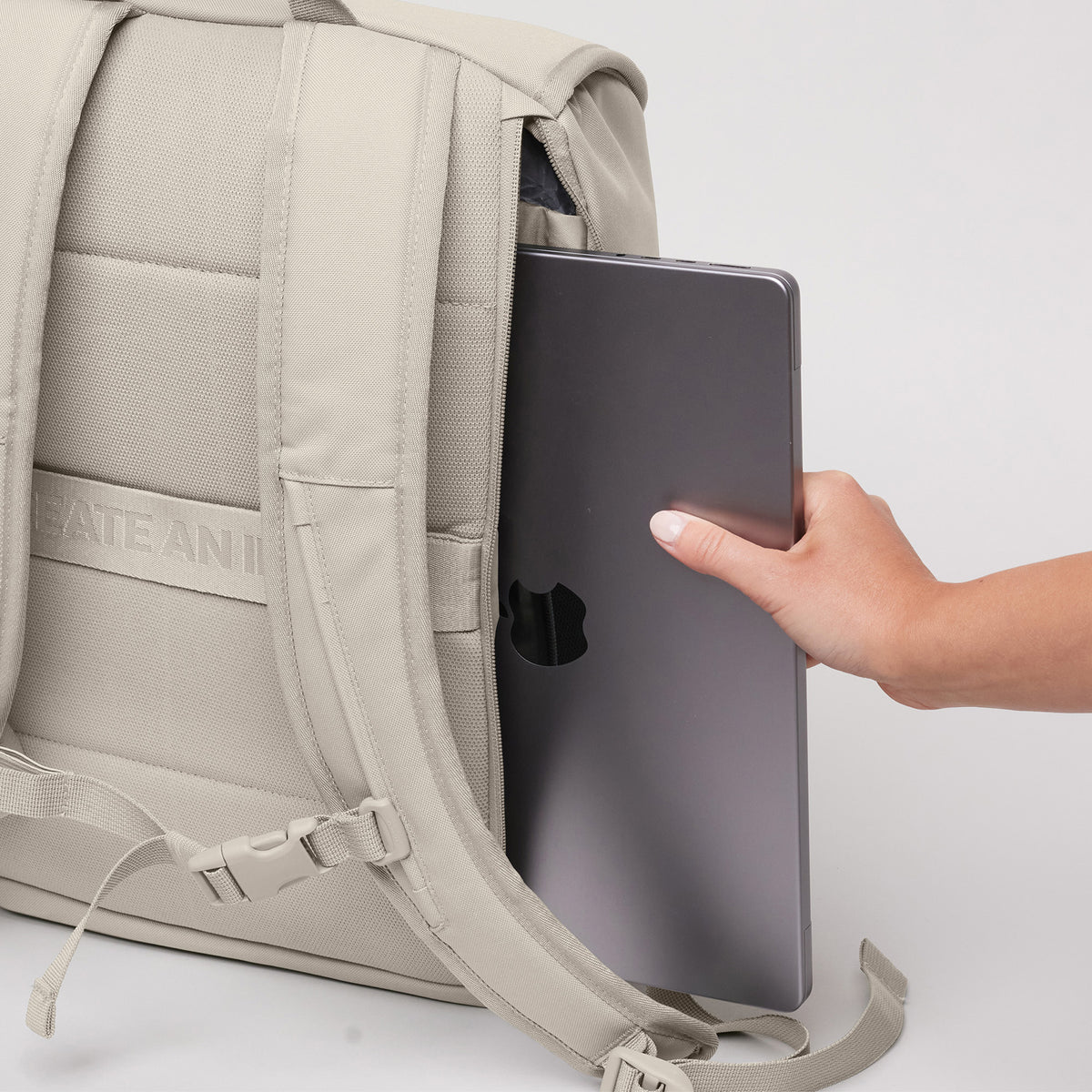 SERENE PACK Rucksack in soft shell (warmes Cremeweiß), eine Frau steckt ein Laptop hinein.