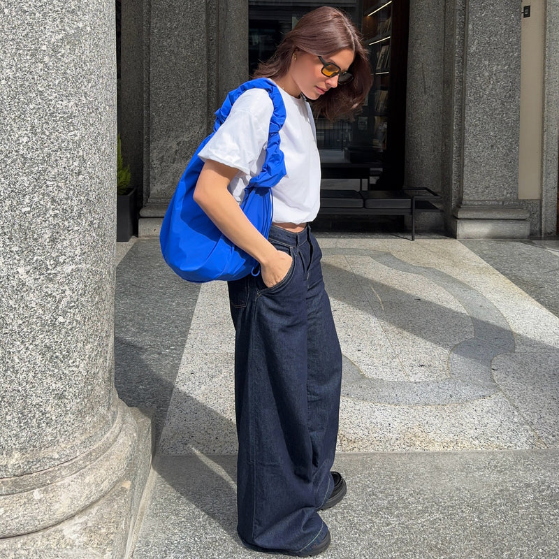 MOON BAG RUFFLE tas in cobalt (Helder kobaltblauw) over de schouder gedragen door een vrouw.