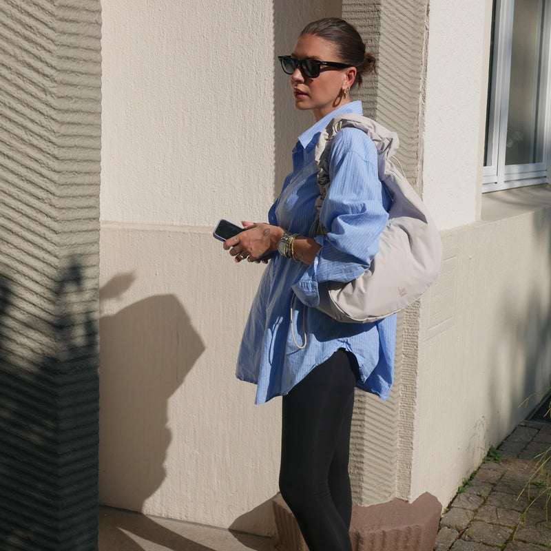 MOON BAG RUFFLE Tasche in soft shell (warmes Cremeweiß) von einer Frau über der Schulter getragen.