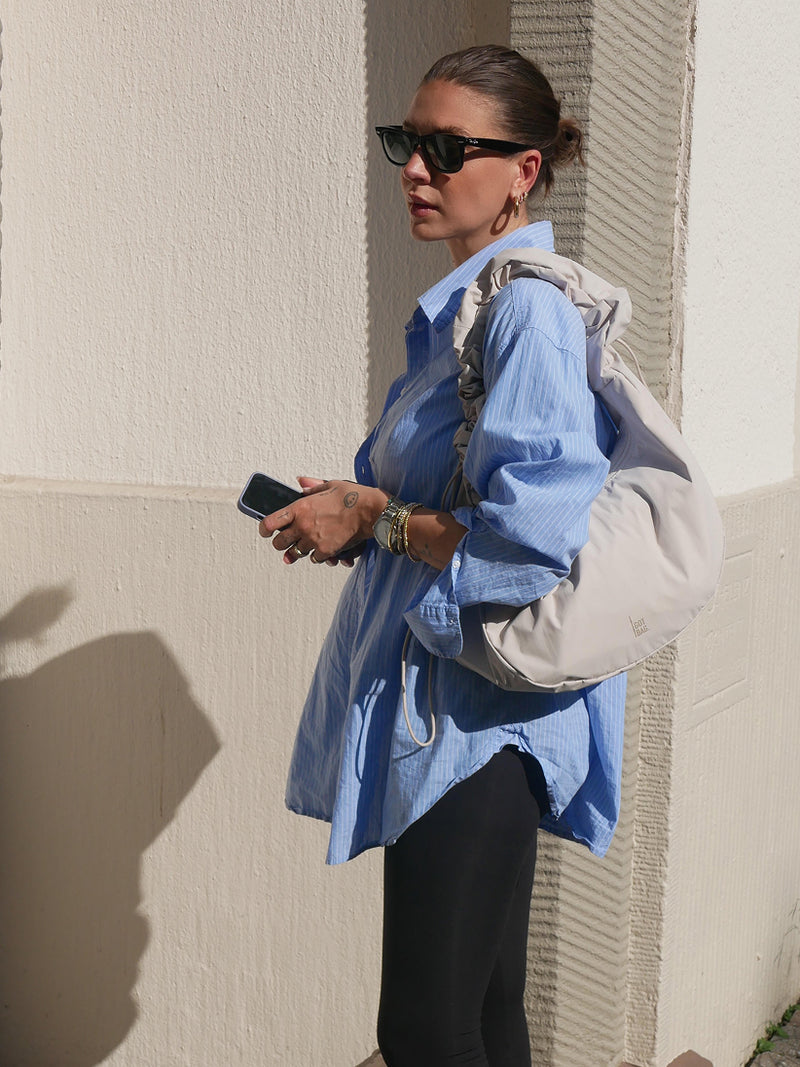 MOON BAG RUFFLE Tasche in soft shell (warmes Cremeweiß) von einer Frau über der Schulter getragen.