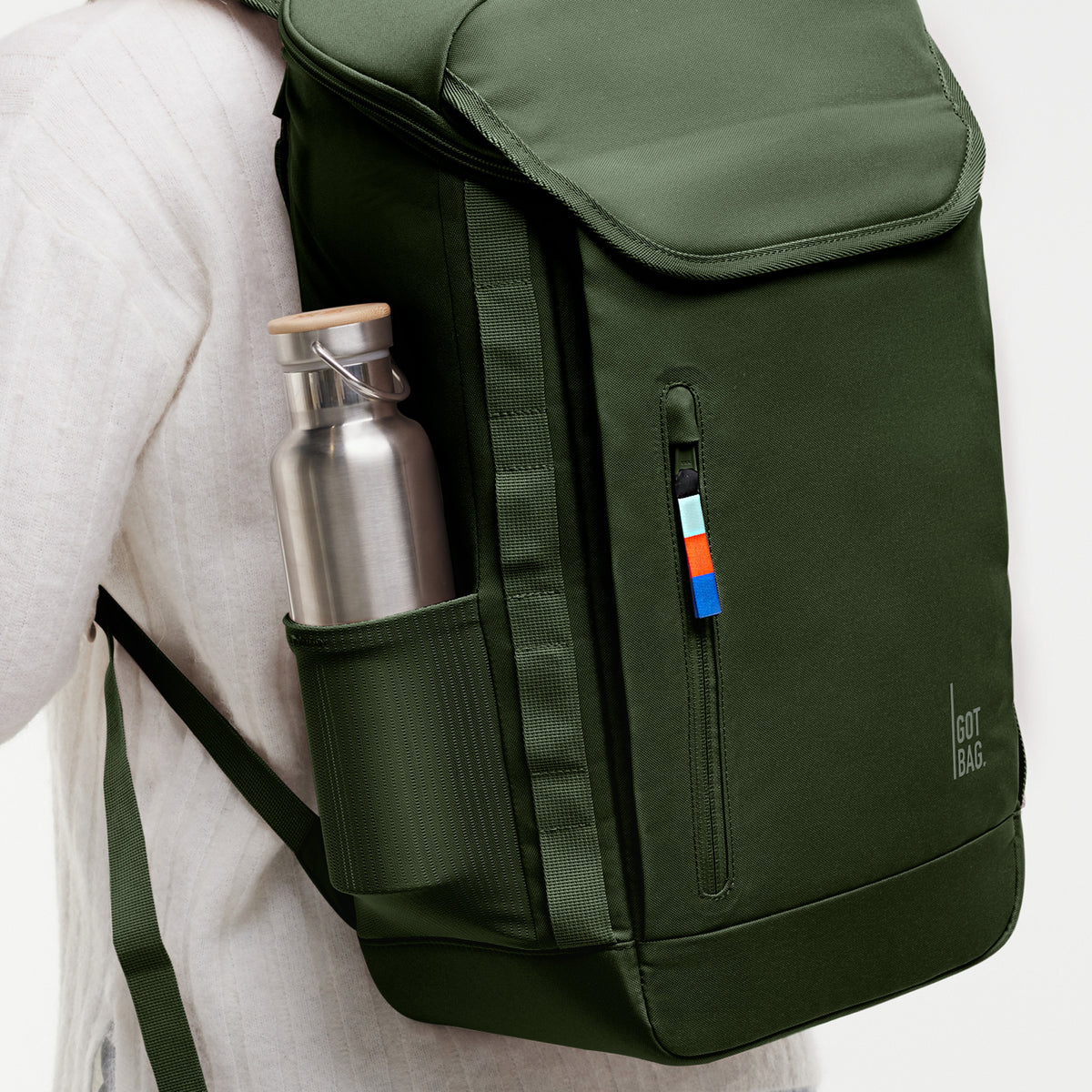 Rucksack von einer Person auf dem Rücken getragen, mit einer Wasserflasche in der Seitentasche.