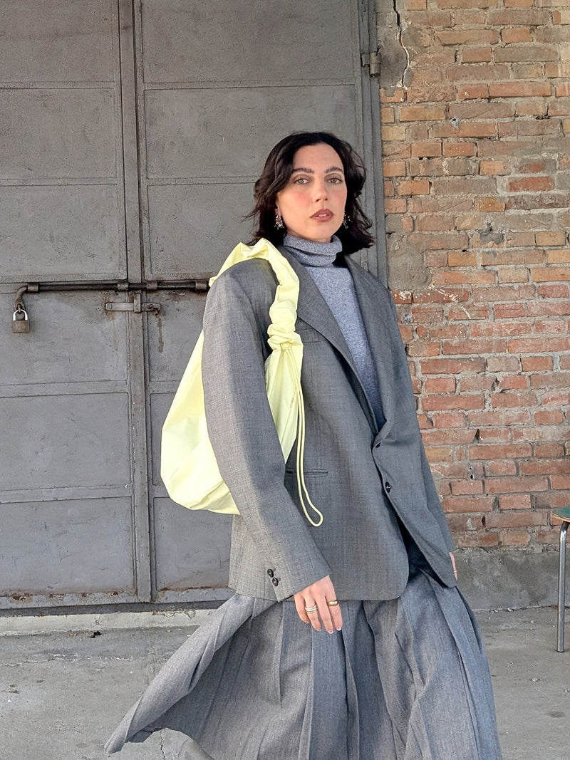 MOON BAG RUFFLE borsa in sea lemon (giallo pastello tenue e delicato) portata a spalla da una donna.