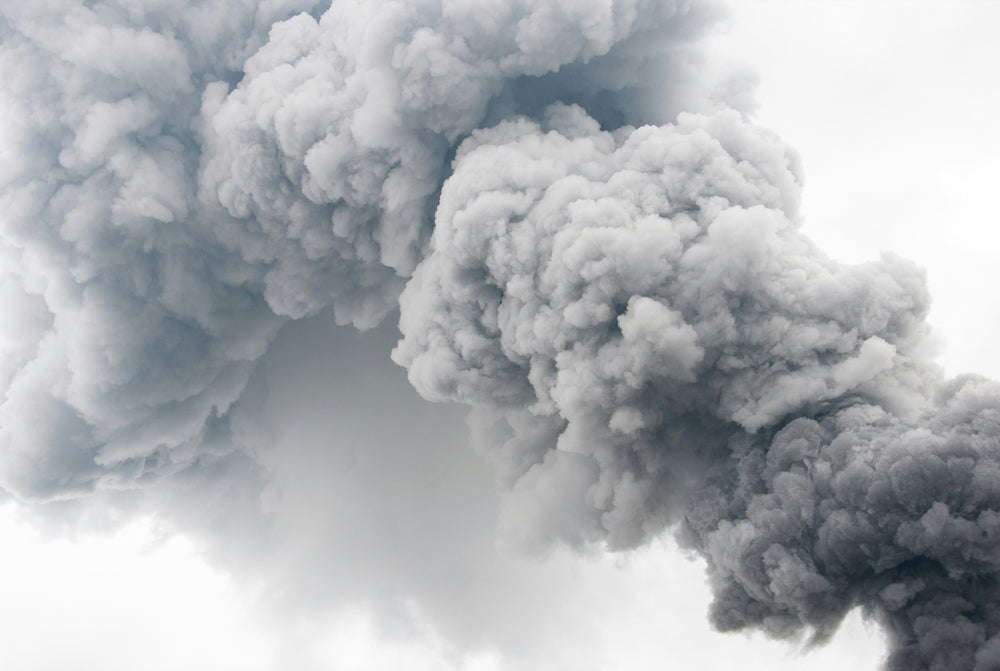 Voluminose, dense e grigie nuvole di fumo come forti emissioni riempiono il cielo chiaro.