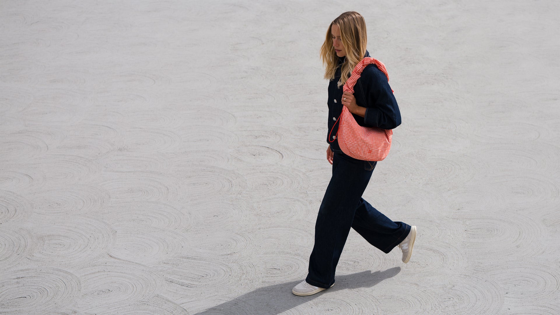 MOON BAG RUFFLE Tasche in vichy hot coral (orange-beige kariert) von einer Frau über der Schulter getragen.