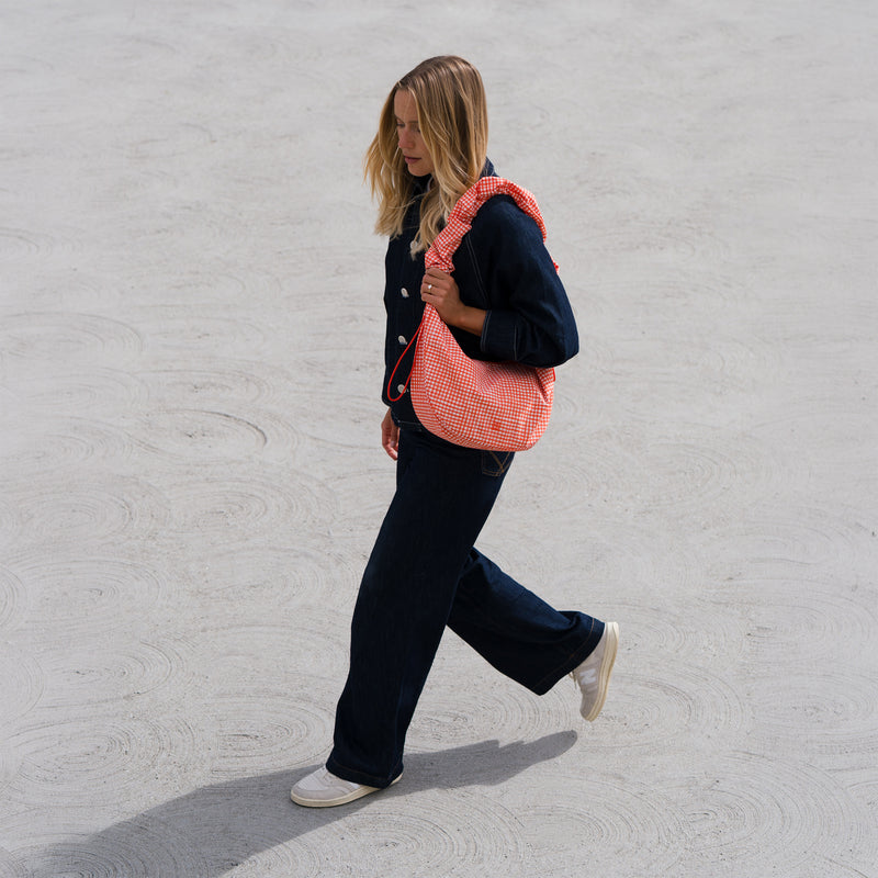 MOON BAG RUFFLE tas in vichy hot coral (Oranje-beige geruit) gedragen door een vrouw.