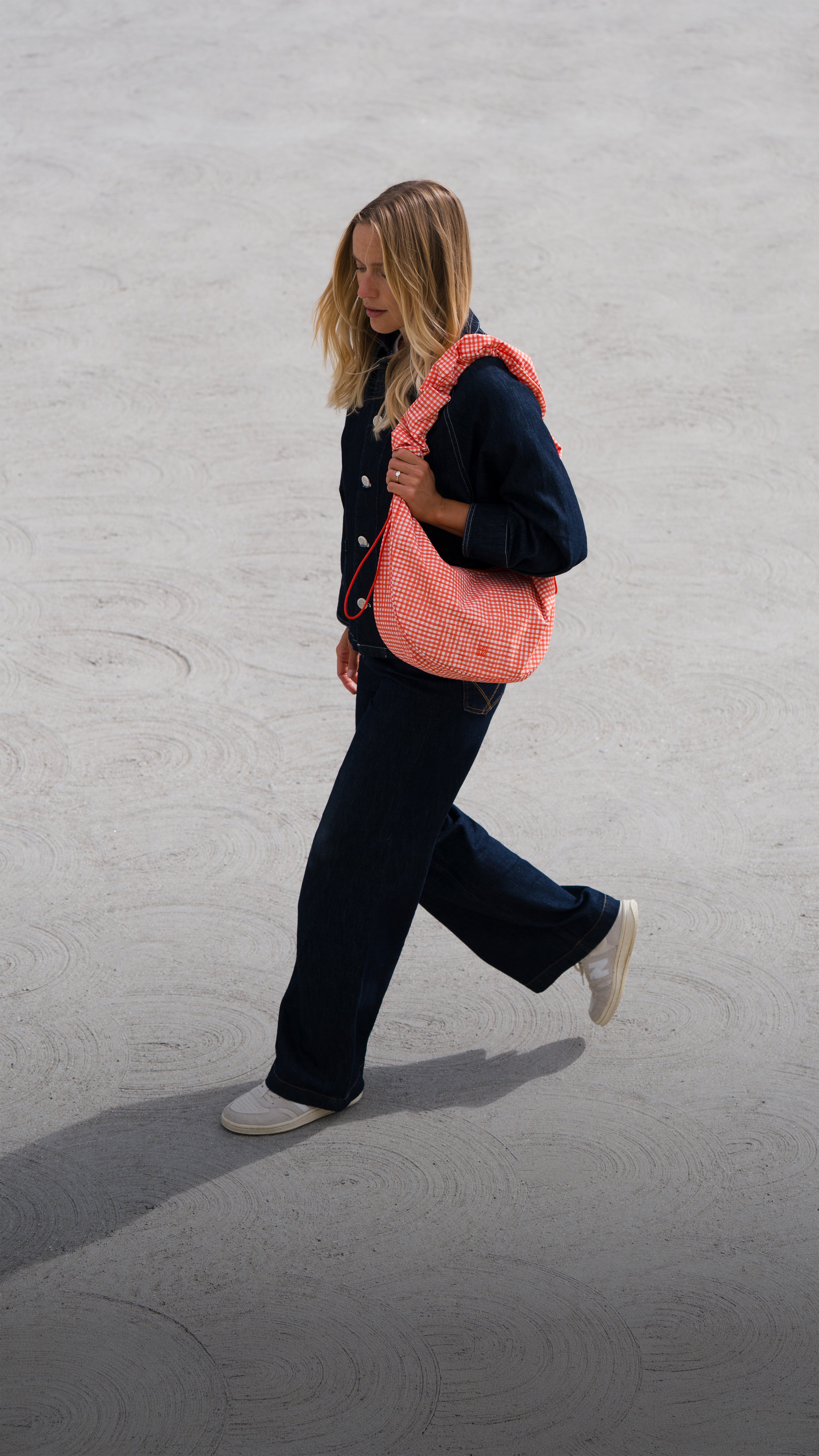 MOON BAG RUFFLE Tasche in vichy hot coral (orange-beige kariert) von einer Frau über der Schulter getragen.