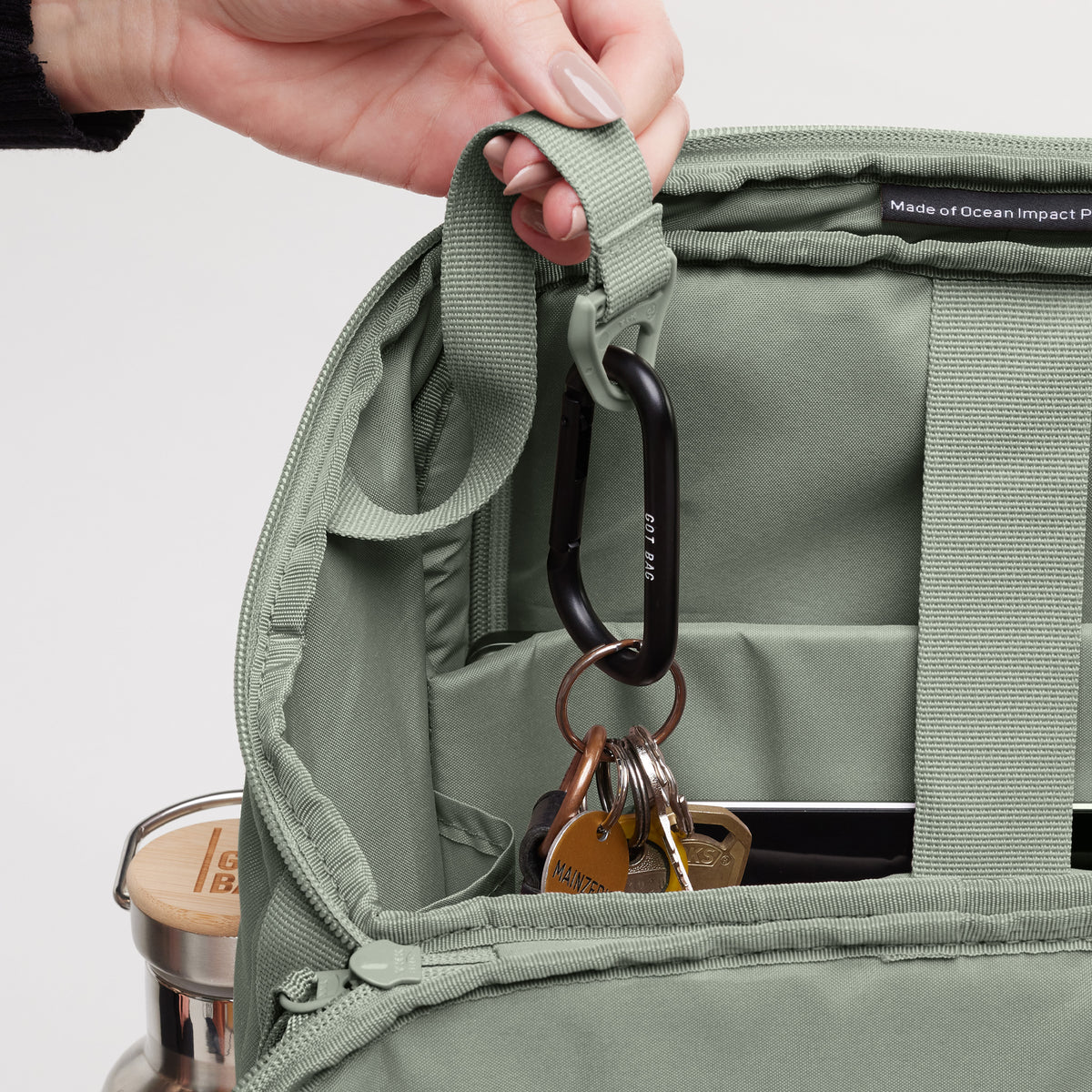 Detailaufnahme vom Inneren einer Tasche mit Schlüsselbund an Karabiner, gehalten von einer Frau.