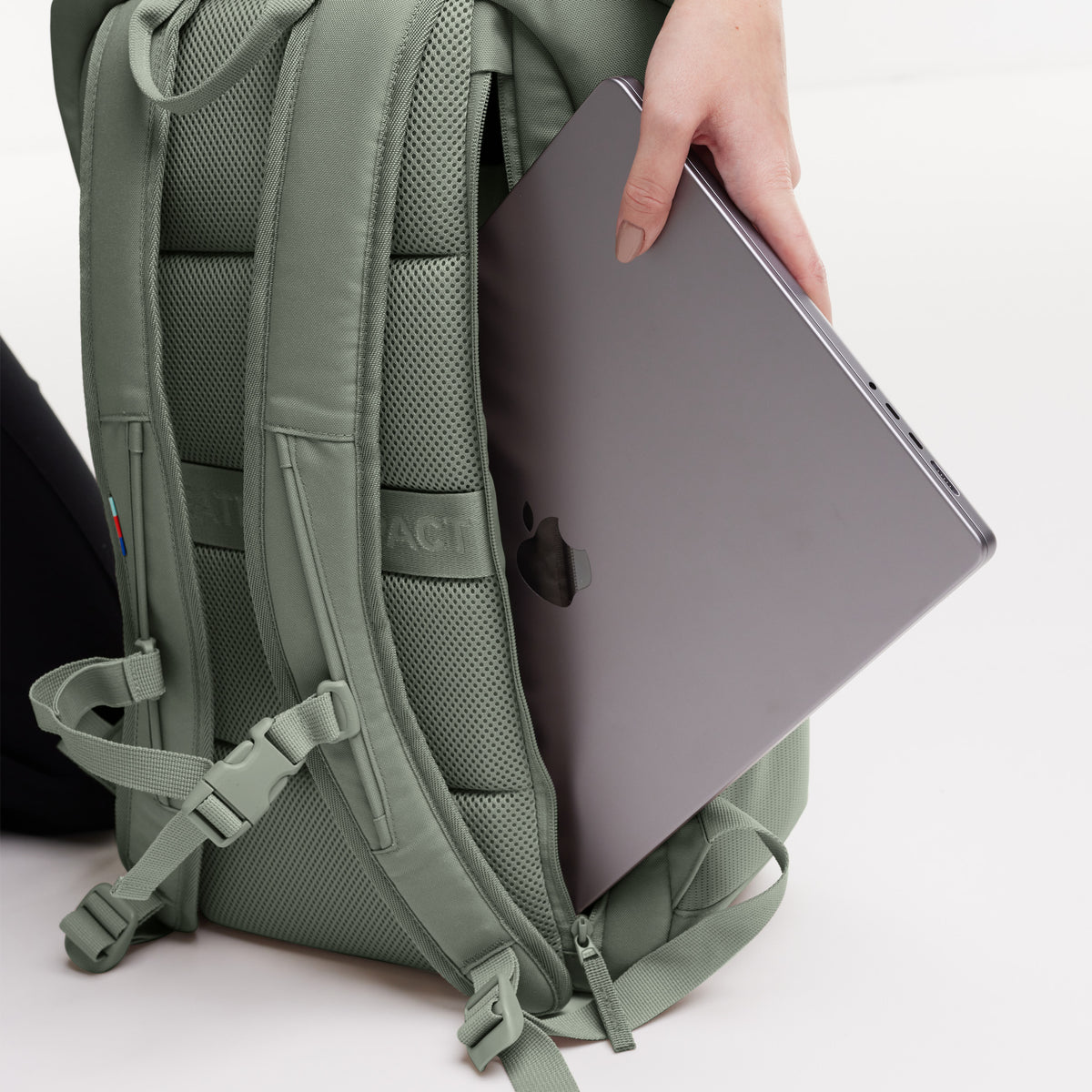 Detailaufnahme des Laptopfachs eines Rucksacks, eine Hand steckt einen Laptop hinein.