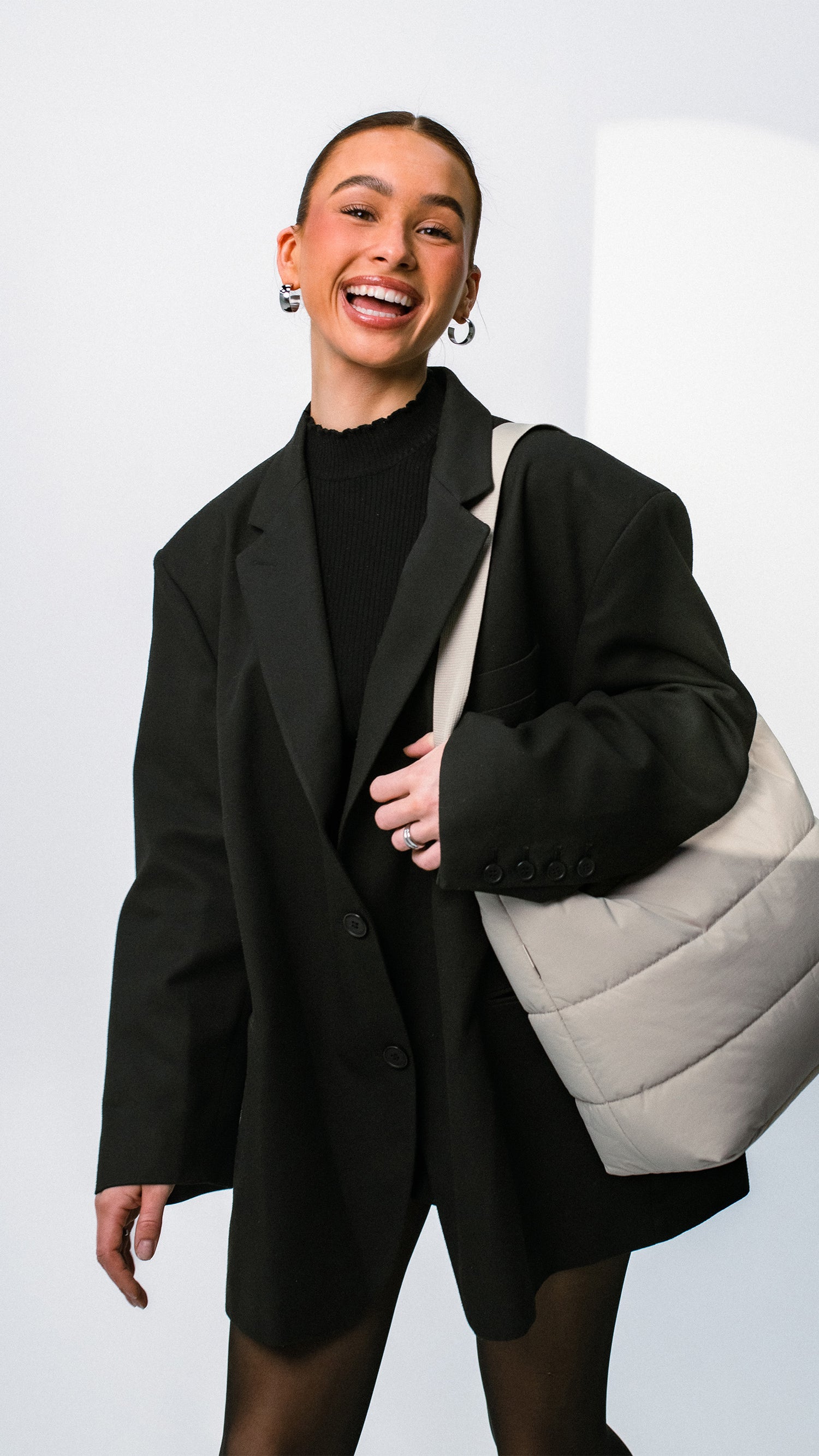 PUFFER SQUARE BAG Tasche in scallop (helles Beige) von einer Frau über der Schulter getragen.