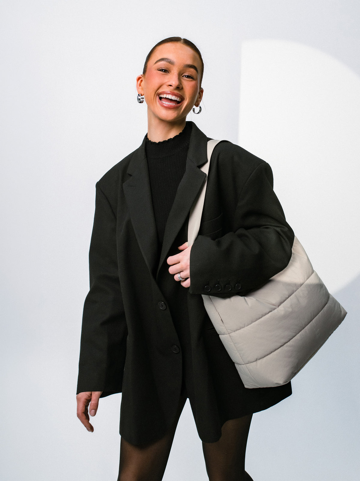 PUFFER SQUARE BAG bolso en scallop (beige claro) llevado al hombro por una mujer.