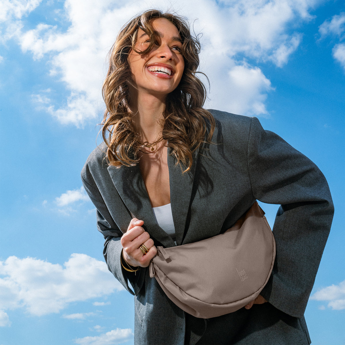 MOON BAG SMALL Tasche in oyster (klassisches Taupe-Braun) von einer Frau in der Hand gehalten.
