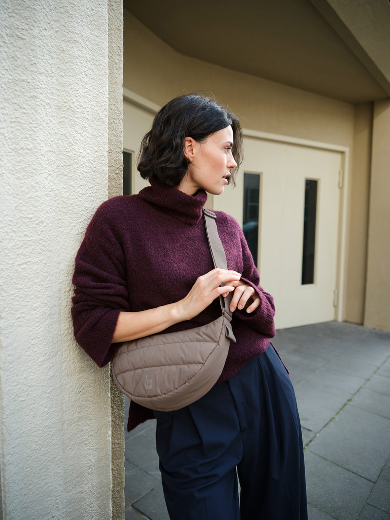 PUFFER MOON BAG tas in oyster (Klassiek taupe-bruin) crossbody gedragen door een vrouw.