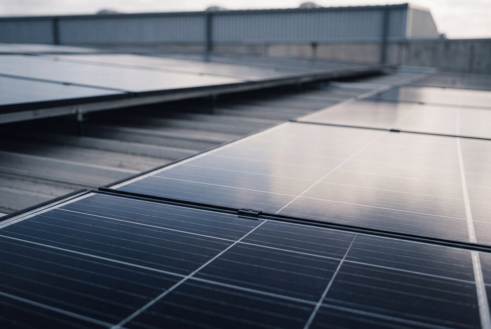 Mehrere Solarmodule als Accessoires auf einem wellenförmigen Blechdach, die den Himmel reflektieren.