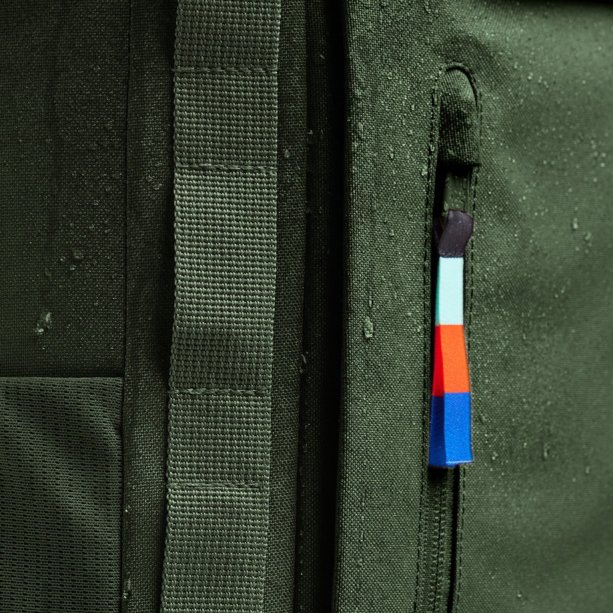 Detailaufnahme von wasserabweisendem Stoff für Accessoires mit Reißverschluss und Wassertropfen.