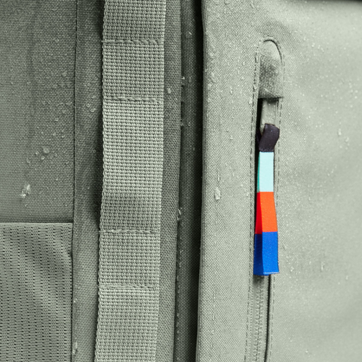 Accessoires Detailaufnahme von wasserabweisendem Stoff mit Reißverschluss und farbigem Zugband.